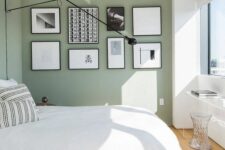 25 an airy Scandinavian bedroom with sage green walls, a bed with neutral bedding, a black and white gallery wall