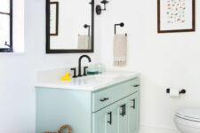 a cute black and white bathroom with a pastel vanity