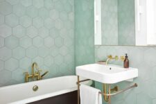 30 a chic bathroom clad with mint hexagon tiles, a black clawfoot bathtub, a free-standing sink and a mirror cabinet