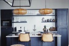 a cool contemporary navy kitchen with white countertops and a backsplash, rattan lamps and leather stools