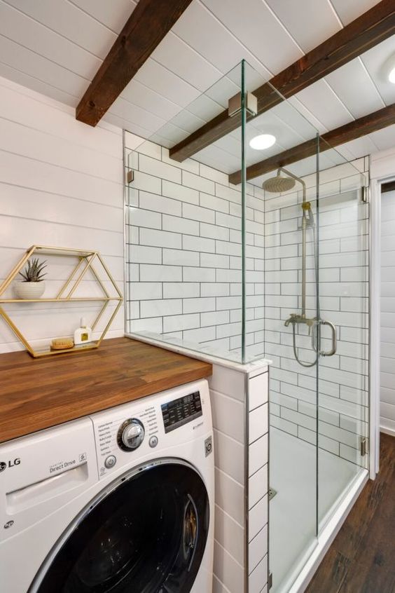 a modern farmhouse bathroom clad with beadboard, white subway tiles, wooden beams and a washing machine