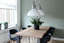 33 a Scandinavian dining room with a sage green accent wall, a stained table and black chairs, pendant lamps