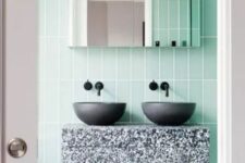 33 a cool and bright bathroom clad with mint skinny tiles, a terrazzo vanity, black sinks and a mirror cabinet is awesome