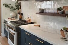 34 a navy shaker style kitchen with a white square tile backsplash and white quartz countertops plus brass touches and floating shelves