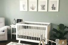 36 a cozy and cute nursery with a sage green accent wall, white furniture, a potted plant, a chic chandelier and a lovely printed rug