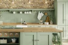 36 a rustic sage green kitchen with elegant vintage cabinetry, wooden countertops and neutral fixtures and handles