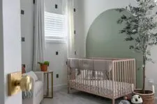 39 a small nursery with a printed wall and a sage green accent, a stained crib with neutral bedding, a potted tree and some toys