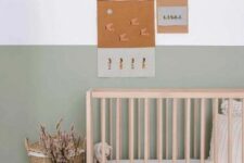 41 an airy and chic Scandinavian nursery with a color block sage green wall, a wooden crib, neutral bedding, a woven basket and a color block vase