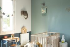 42 an airy Scandinavian nursery with a sage green accent wall, a wooden crib, a small desk and a chair, some lovely decor