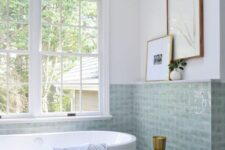 46 an airy bathroom in neutrals, with sage green tiles, an oval tub, a side table and artwork is a lovely and chic space