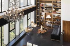 46 an open layout with a glazed wall, a large bookcase, a black sofa, neutral chairs, a living edge table, a chic chandelier, a stained table and neutral chairs