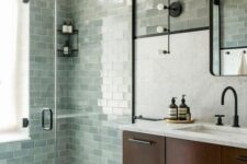 47 a farmhouse sage green bathroom clad with subway tiles, a dark-stained floating vanity and black fixtures
