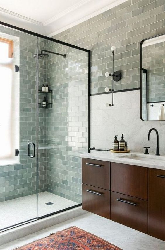 A farmhouse sage green bathroom clad with subway tiles, a dark stained floating vanity and black fixtures