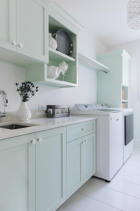 a mint green laundry room with elegant shaker cabinets, open shelves, a washing machine and a dryer, white stone countertops