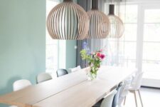 53 a Scandinavian dining room with a mint green accent wall, a stained table and mismatching chairs plus oversized lamps