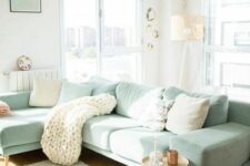 55 a Scandinavian living room with a mint green sectional, neutral and mint pillows, a knit blanket, a side table and a floor lamp