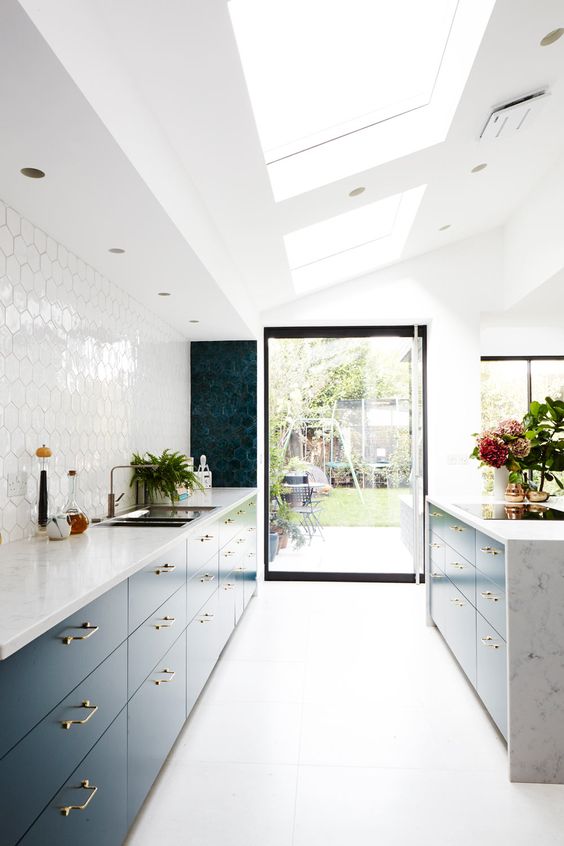 a chic contemporary kitchen with lower flat panel cabinets and a kitchen island, a glossy white hex tile backsplash and skylights for natural light