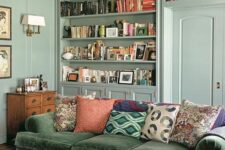 56 a vintage mint green living room with built-in bookshelves, a green sofa and bright pillows, a stained table and a sideboard