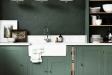 58 a moody hunter green kitchen with vintage cabinets, dark green brick walls, a white stone backsplash and countertops