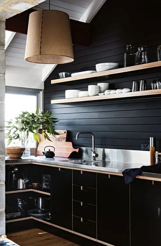 a black kitchen with contrasting light-colored shelves, handles and countertops plus a burlap pendant lamp