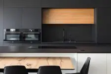 a contemporary kitchen with sleek black cabinets and a white kitchen island, black soapstone countertops, a table and black chairs