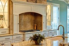 a creamy kitchen with shaker cabinets, a cooker with a built-in hood, a stained kitchen island and neutral granite countertops