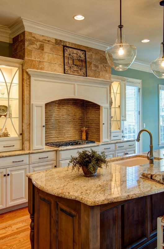 A creamy kitchen with shaker cabinets, a cooker with a built in hood, a stained kitchen island and neutral granite countertops
