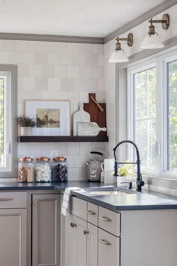 a dove grey kitchen with flat panel cabinets and shaker style ones, black soapstone countertops, an open shelf and a square tile backsplash