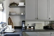 a light grey shaker cabinet kitchen with open shelves, black soapstone countertops and a slight vintage feel