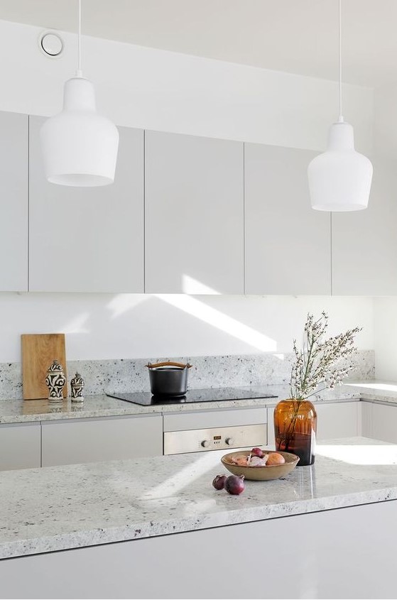a minimalist grey kitchen with grey terrazzo countertops and white pendant lamps is a chic and welcoming space