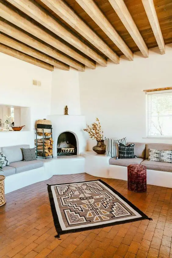 a modern Sapnish living room with wooden beams and a terracotta tile floor, a hearth, built-in seatings, printed texiles