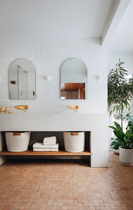 a modern bathroom clad with white skinny tiles and square terracotta ones, a large neutral vanity and potted plants