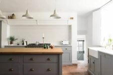 a modern farmhouse kitchen with lower grey cabinets and a large kitchen island, a terracotta tile floor and pendant lamps