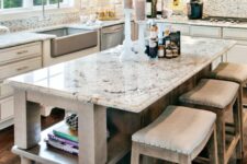 a neutral farmhouse kitchen with shaker cabinets, a vintage whitewashed kitchen island, white granite countertops and a backsplash