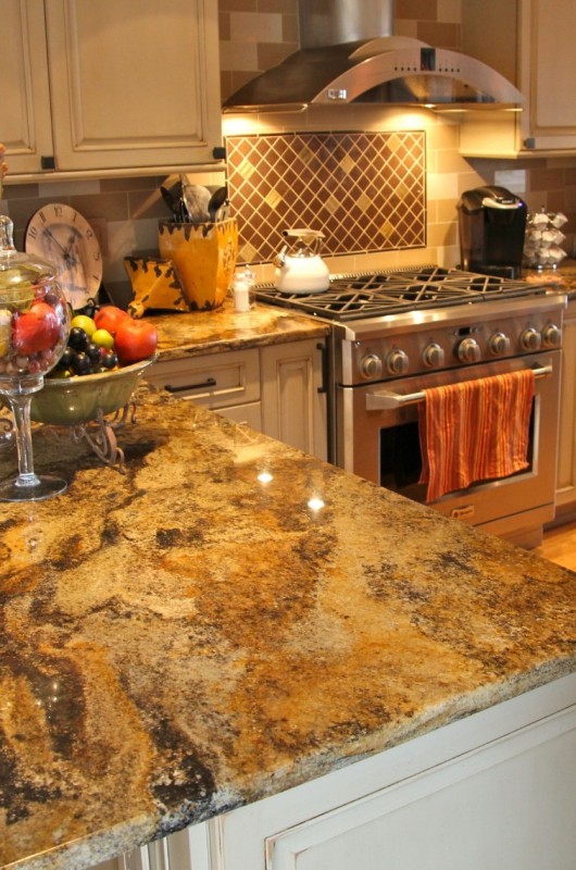 a neutral kitchen with white shaker cabinets, a neutral tile backsplash, gold and white granite countertops is very chic