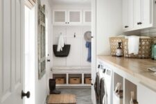 a neutral mudroom laundry with shaker cabinets, butcherblock countertops, a washing machine and a dryer plus black fixtures