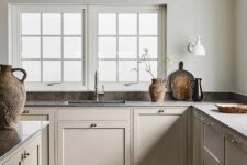 a refined greige kitchen with shaker style cabinets, only lower cabinets, grey soapstone countertops and lots of natural light
