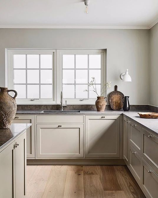 a refined greige kitchen with shaker style cabinets, only lower cabinets, grey soapstone countertops and lots of natural light