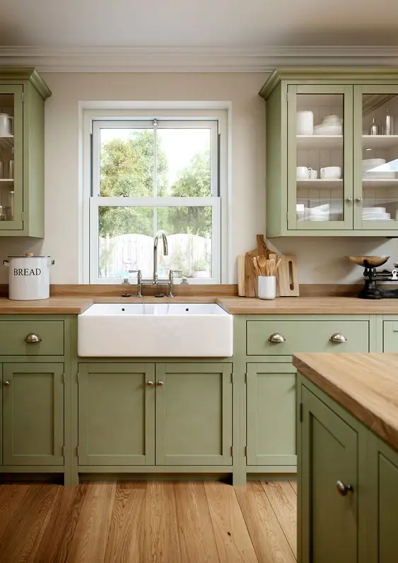 a sage green kitchen with shaker cabinets, butcherblock countertops, a large matching kitchen island is welcoming