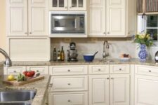 a traditional creamy kitchen with shaker cabinets, a matching tile backsplash and grey granite countertops