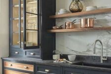 a vintage black kitchen with shaker and glass front cabinets, black soapstone countertops and stained open shelves