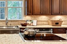 a vintage rich-stained kitchen with shaker cabinets, a tan and beige tile backsplash and matching granite countertops