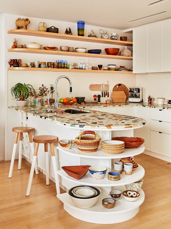 a vivacious white kitchen with flat panel cabinets, a colorful terrazzo countertop, open shelves for displaying dishes