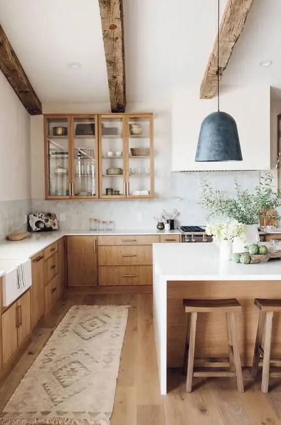 A welcoming modern farmhouse kitchen with light stained cabinets, wooden beams and stools that warm up the space