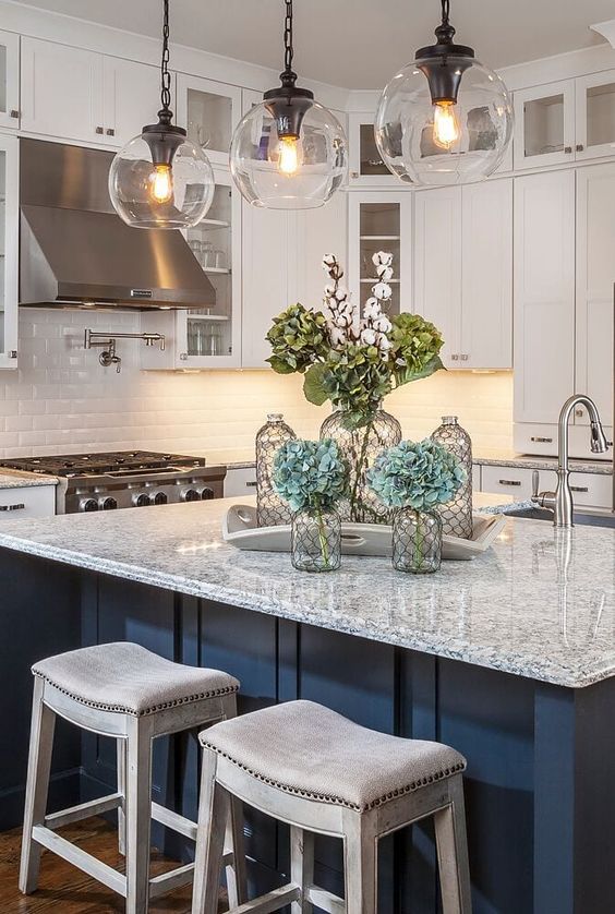 a white kitchen with shaker cabinets, a white subway tile backsplash, a navy kitchen island, grey granite countertops and pendant lamps