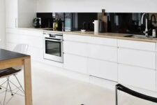 a white minimalist one wall kitchen with blonde butcherblock countertops, a black glass backsplash and an eating zone