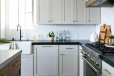 a white shaker style kitchen with black soapstone cabinets, a stained kitchen island and neutral countertops, black fixtures