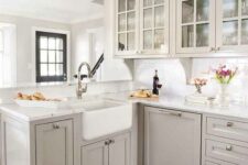 an airy grey kitchen with inlay and glass cabinets, a white subway tile backsplash and white quartz countertops
