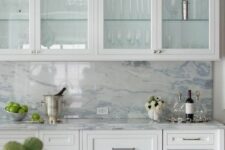 an exquisite white kitchen with inlay and glass cabinets, a white and blue quartz backsplash and countertops is wow