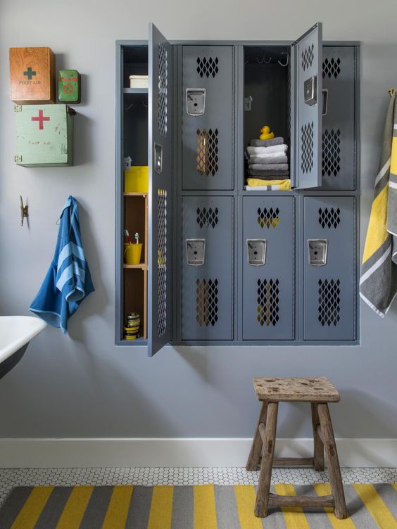 A vintage inspired bathroom with grey built in lockers, bright mini cabinets and a bold striped rug is a cool idea
